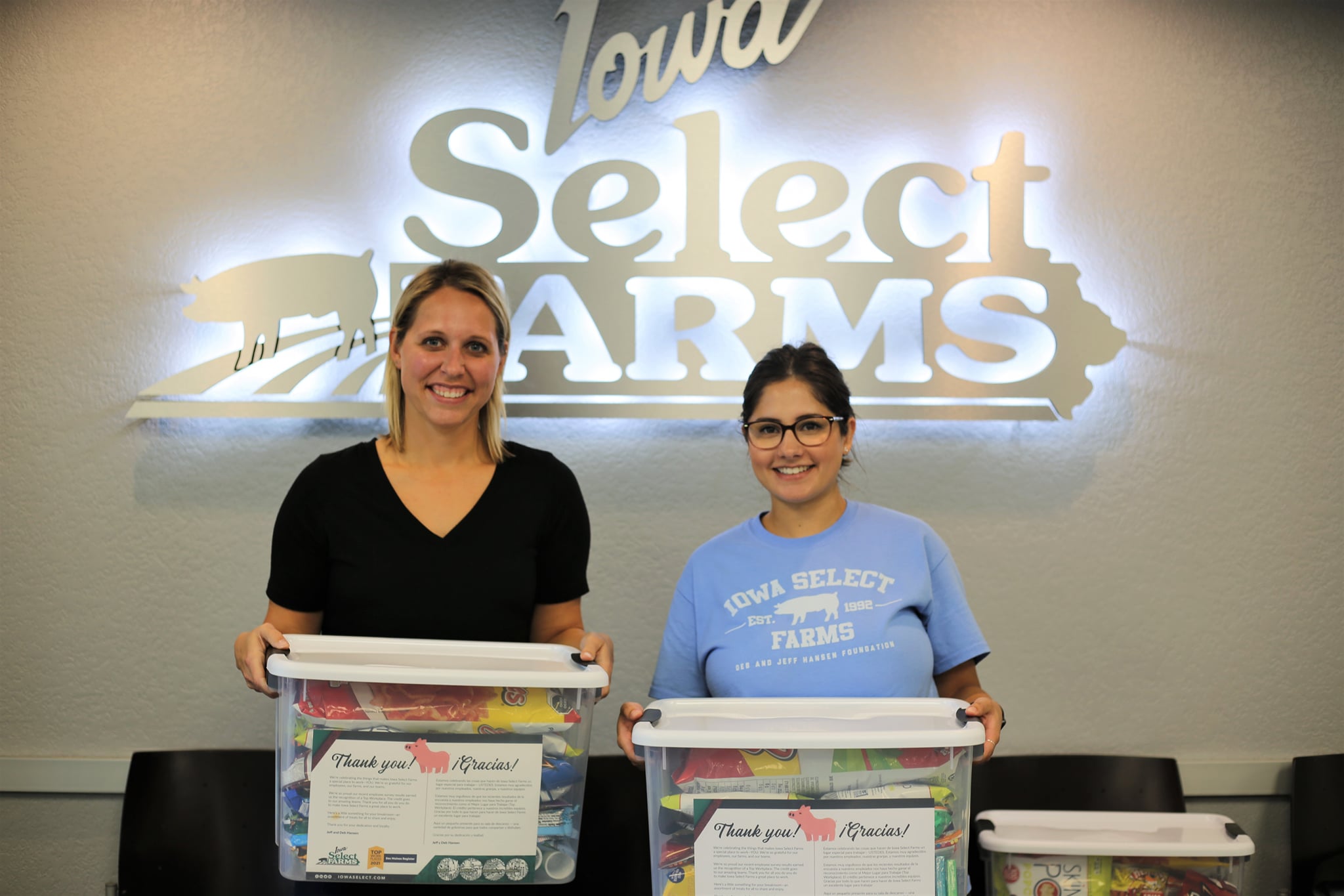 Two women hold totes full of snacks.