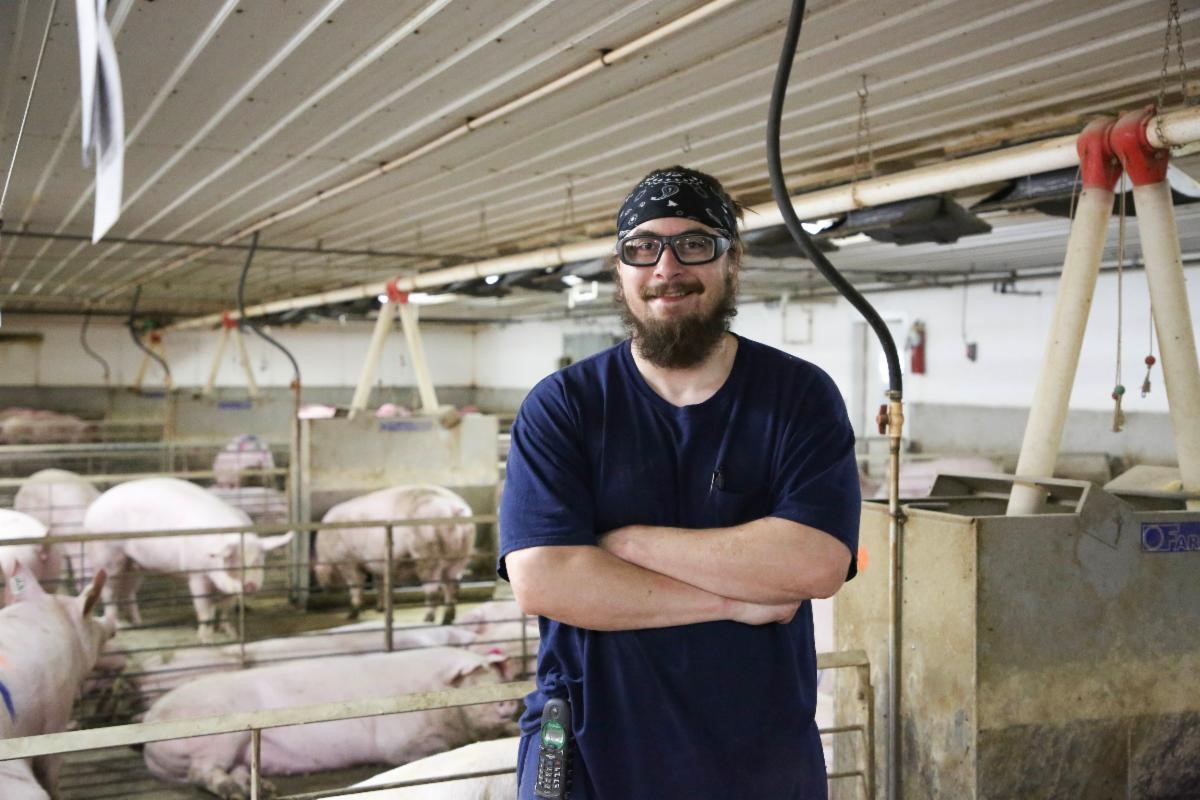 Bryce standing inside hog barn