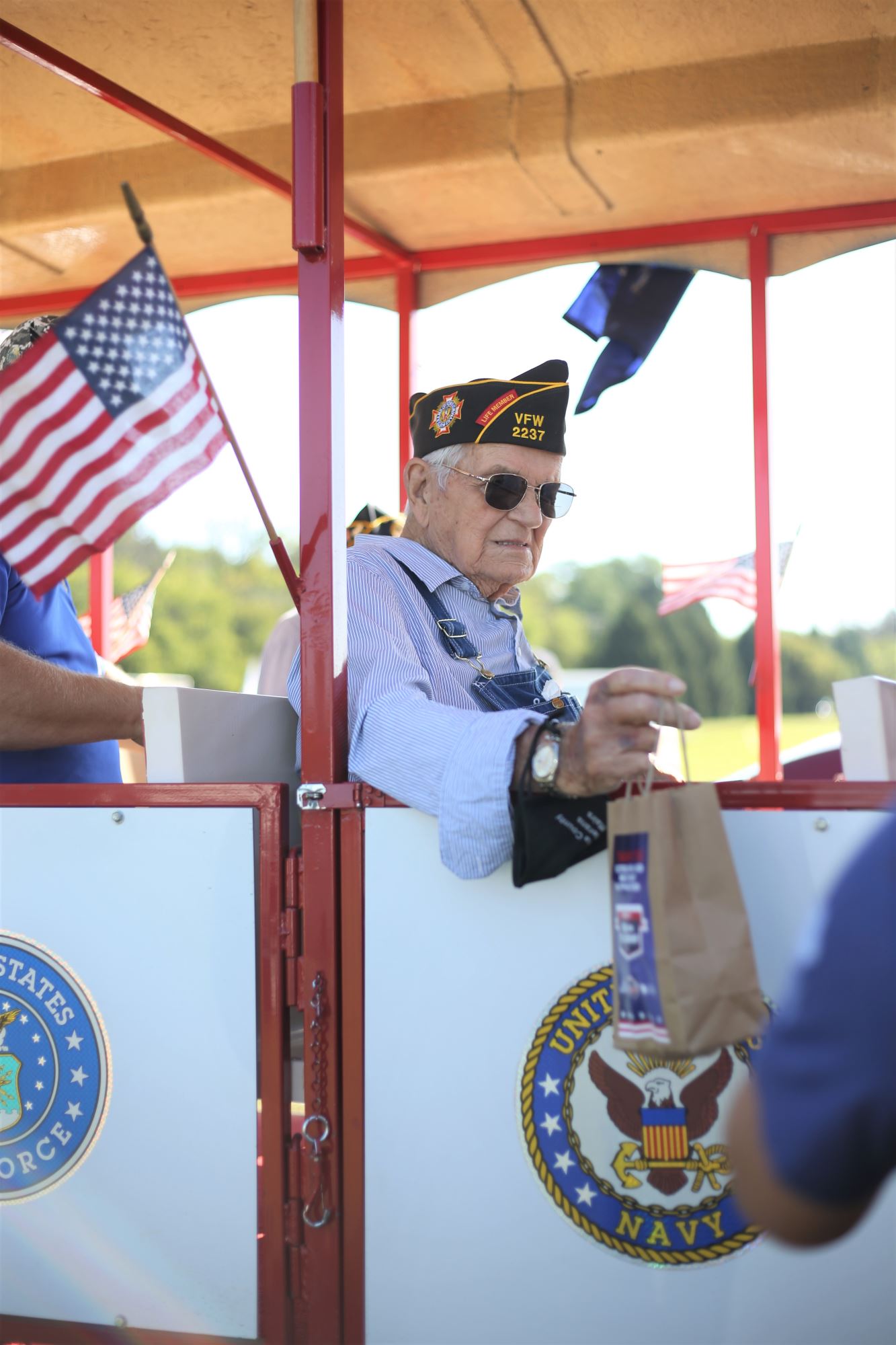 Veteran sits on trolley and grabs a bag of food.