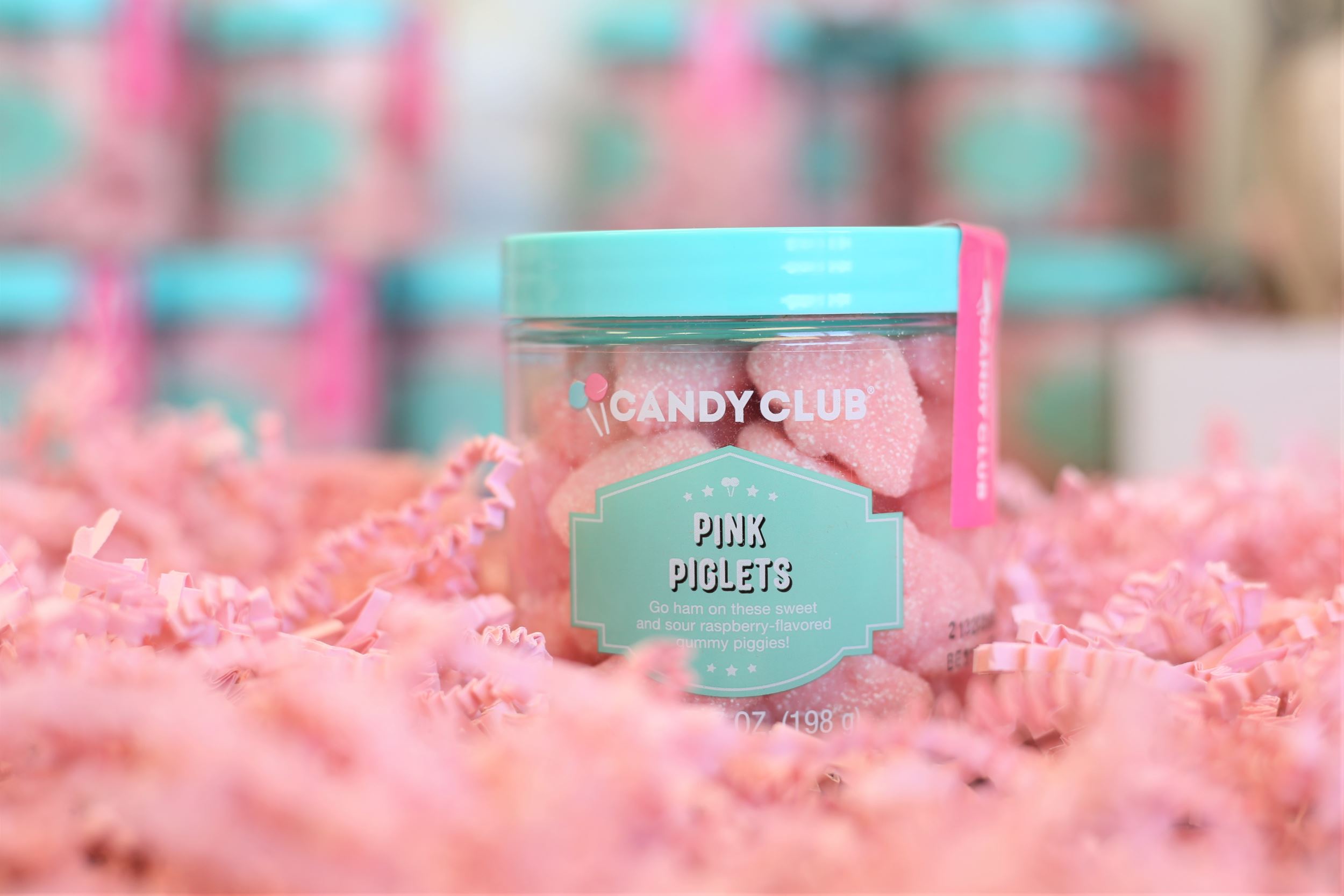 Container full of pink candy sitting in pink confetti.