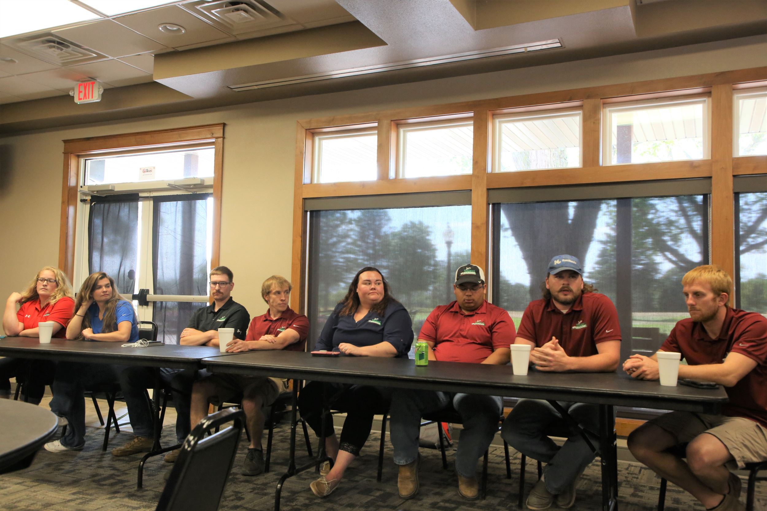 The panel sits at a long table at the front of the room.