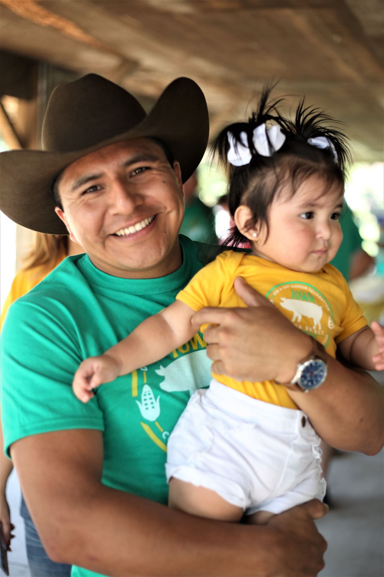 A man in a cowboy hat holds a baby.
