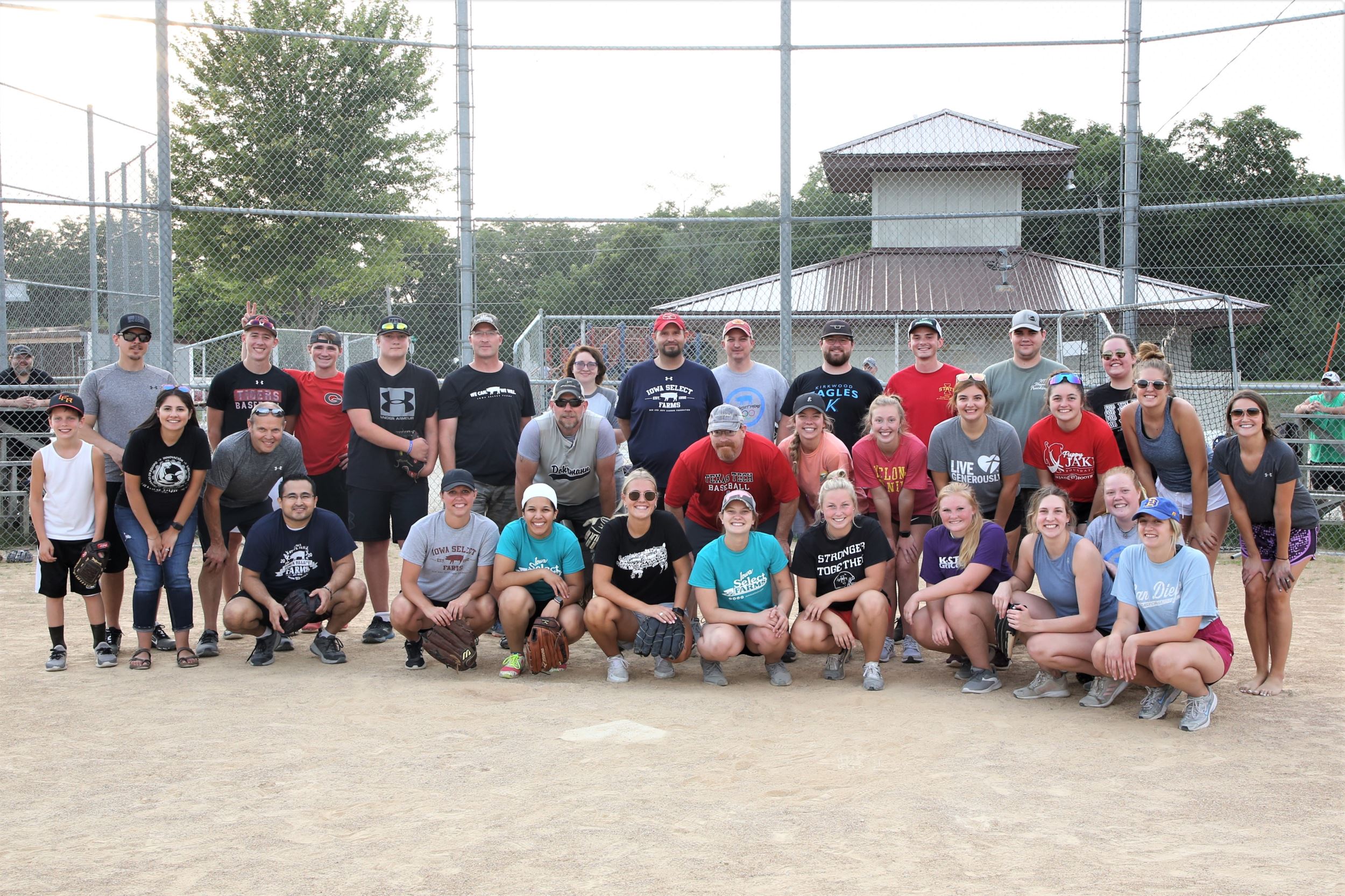 Both softball teams pose for a group picture on the diamond.