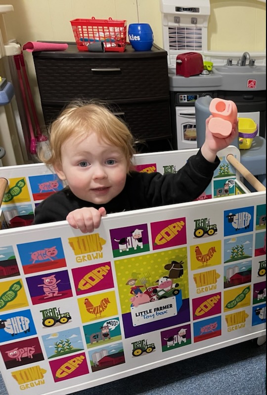 A young boy sits in a toy box