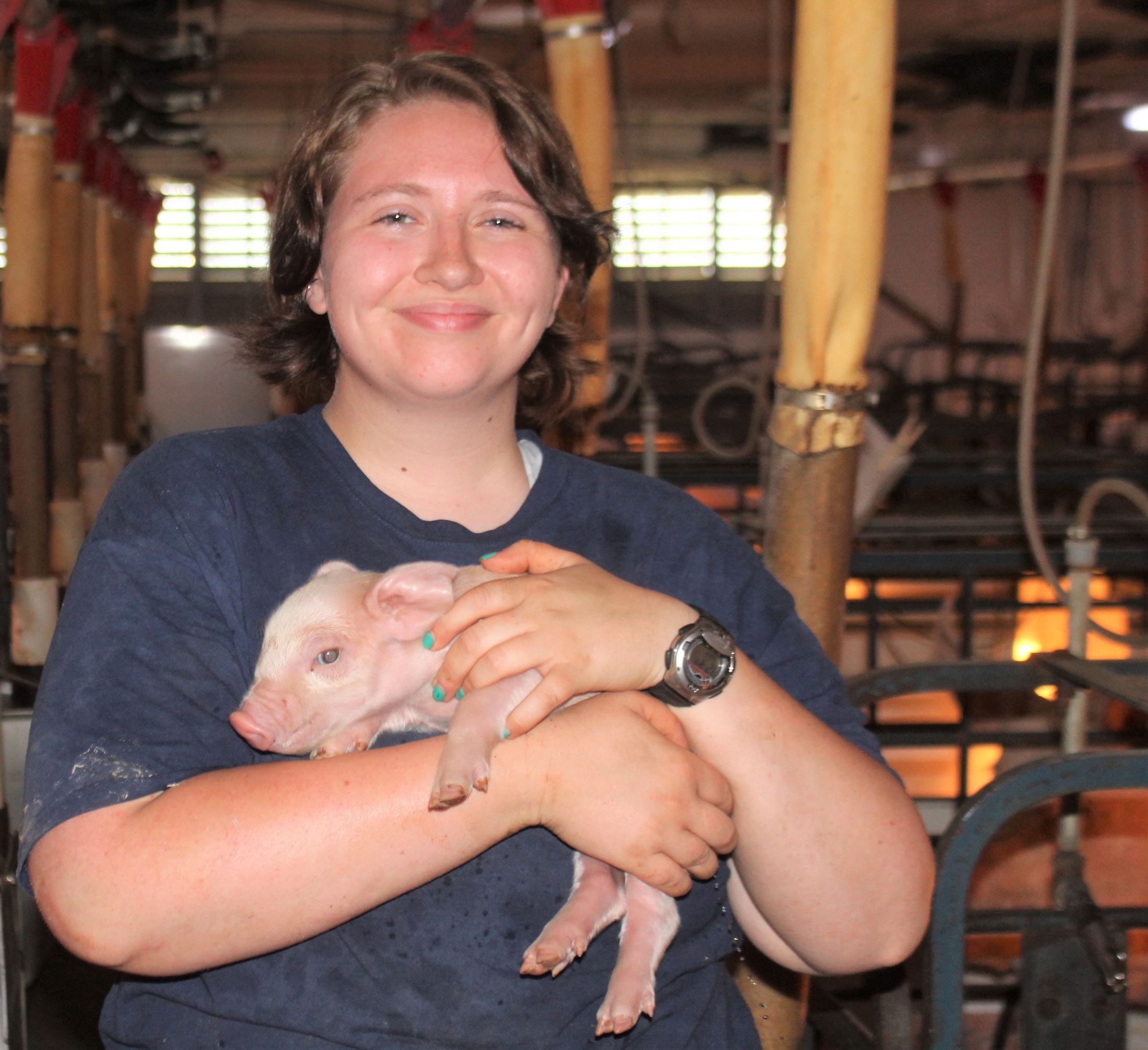 Megan holds a baby pig.