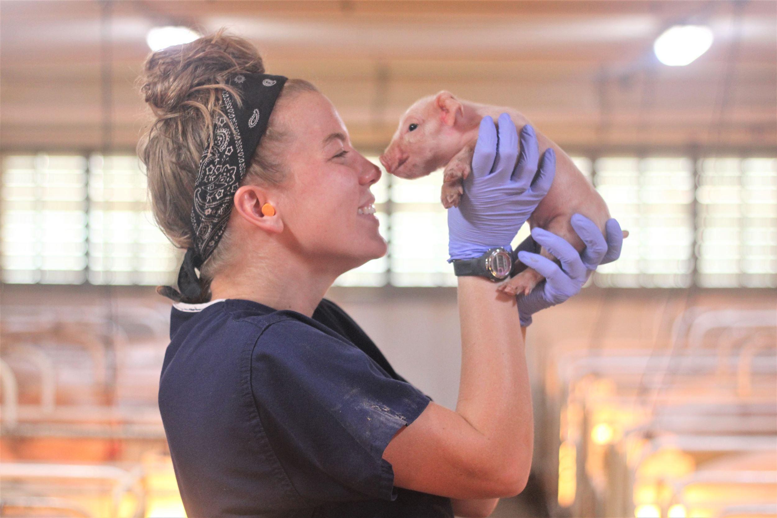 Emily holds a small baby pig.