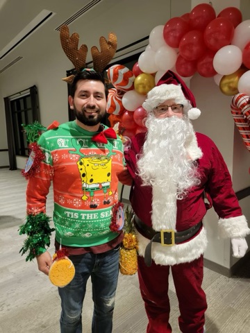 santa poses with someone wearing an ugly sweater
