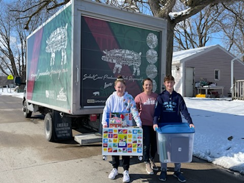 volunteers hold toy boxes by an Iowa Select Farms truck