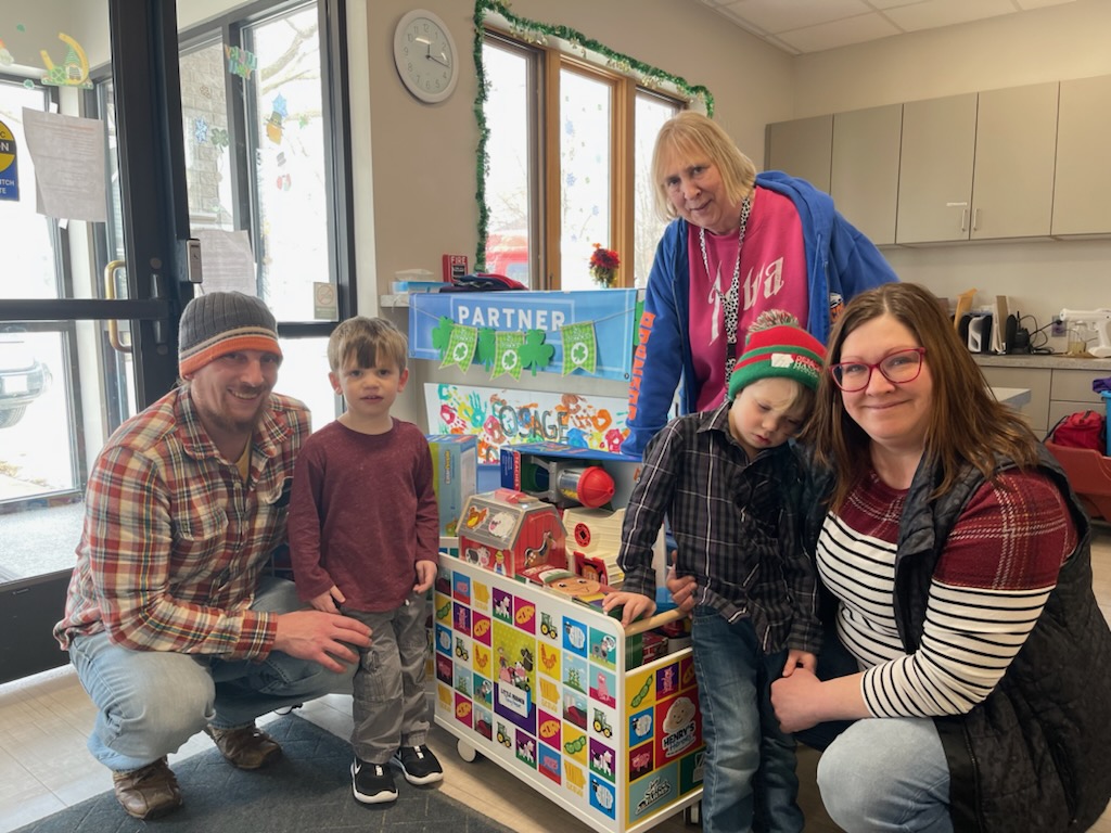 kids and adults pose by toybox for a group picture