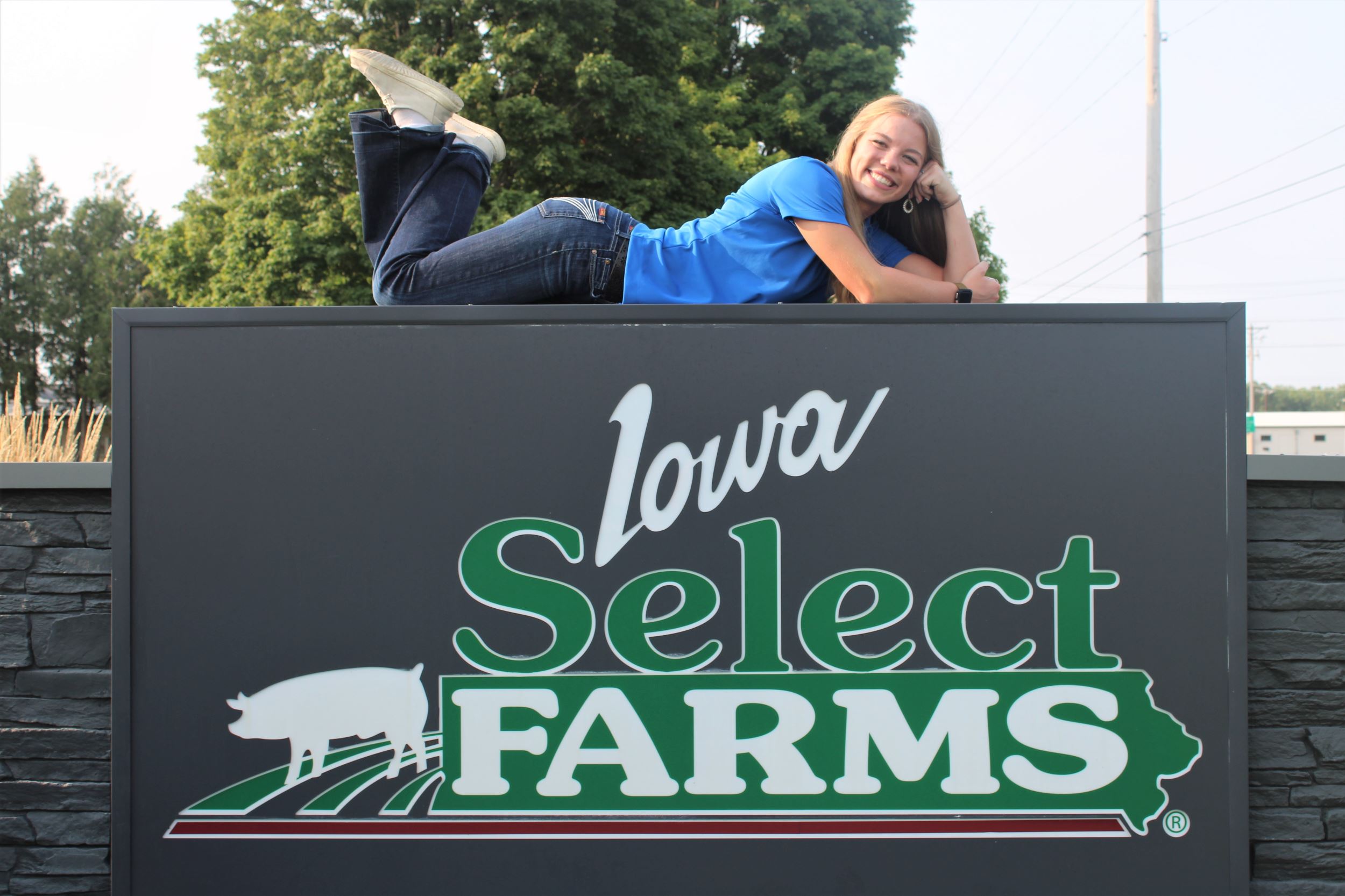 Emily lays on top of the Iowa Select Farms sign.