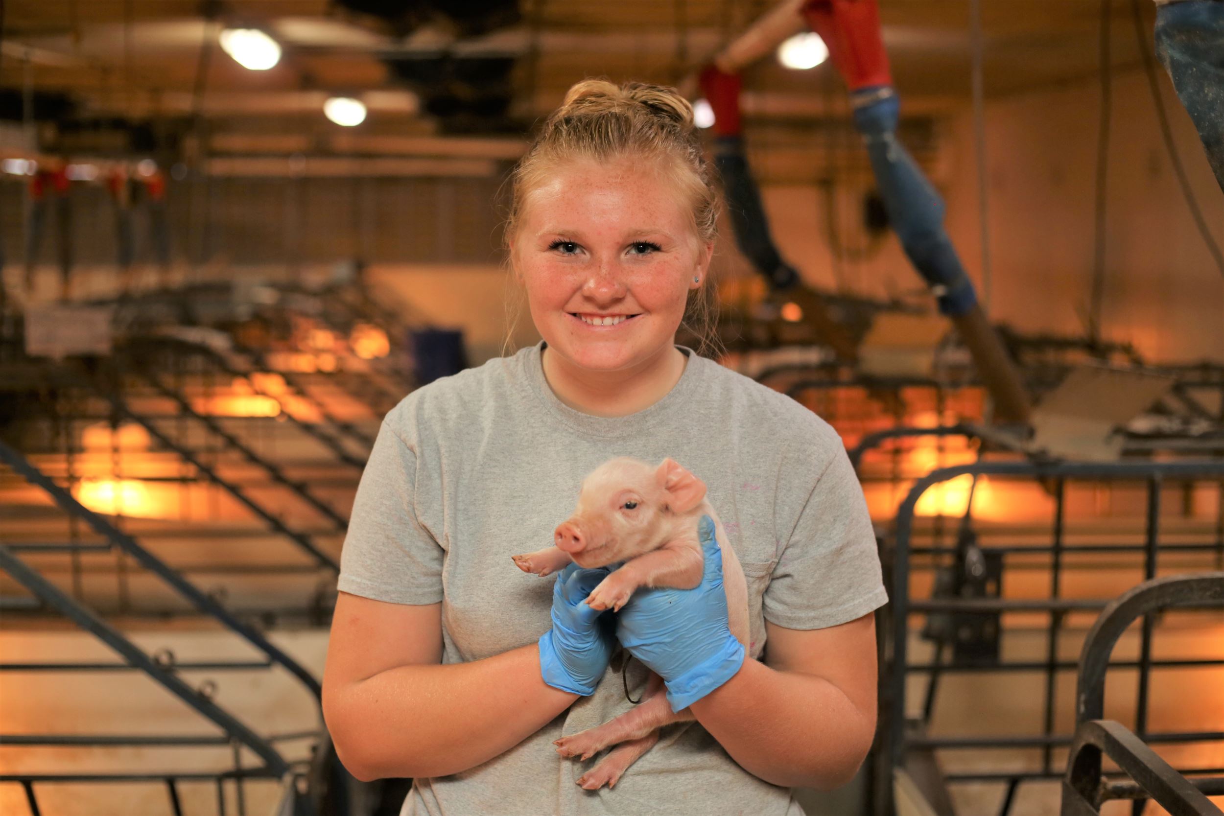 Kenzie holds a baby piglet.