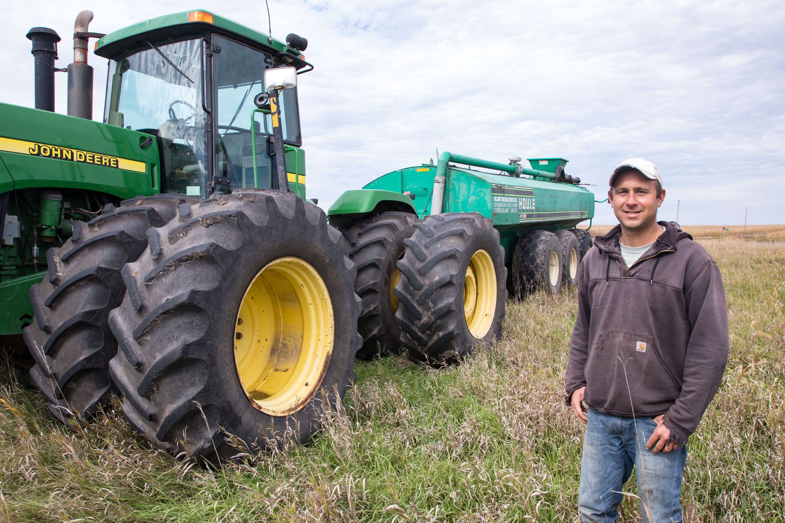 Brandon standing next to his farming equipment 